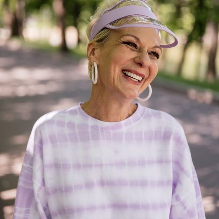A woman laughing outdoors on a tree-lined path